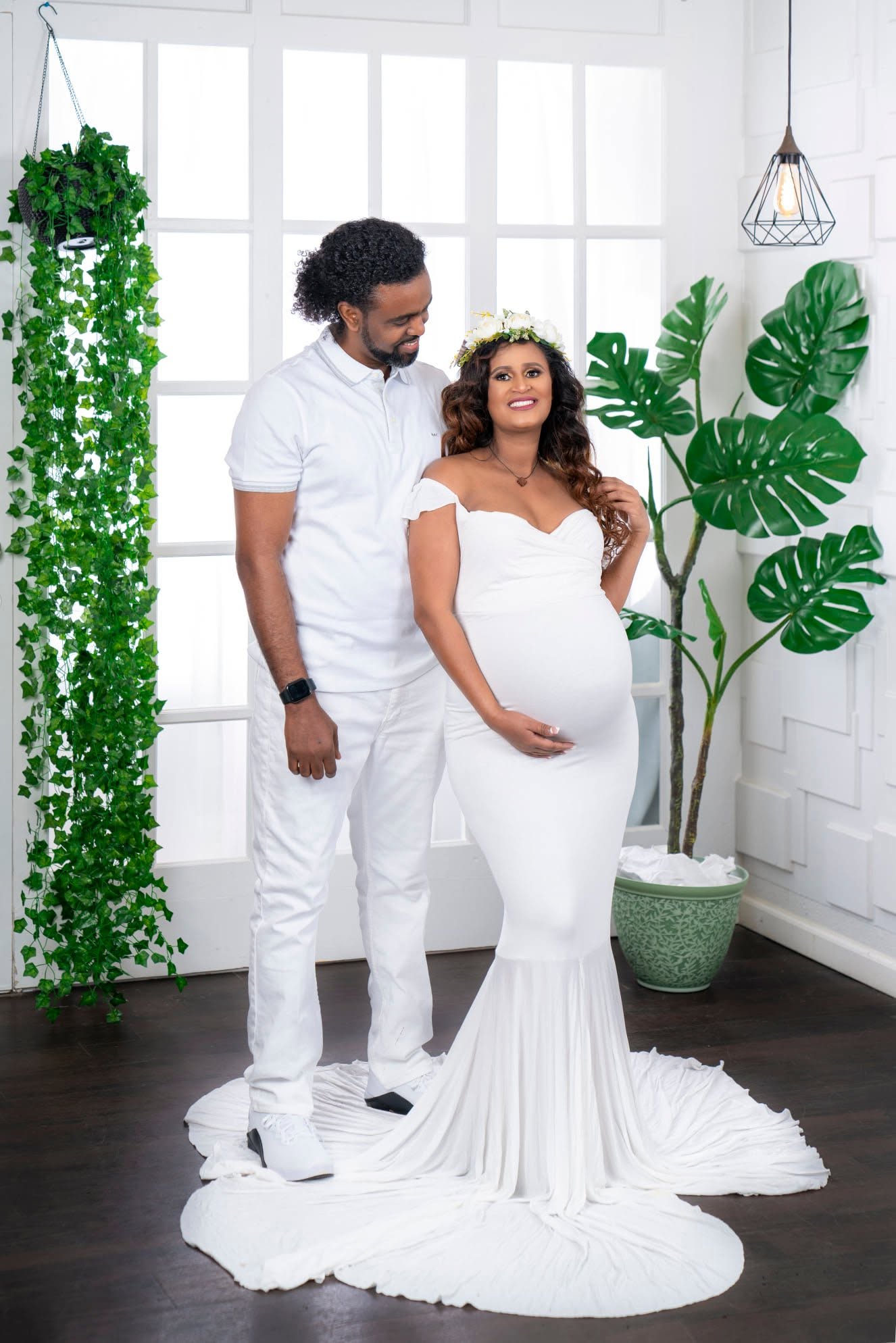 Expectant couple in white at an indoor maternity session